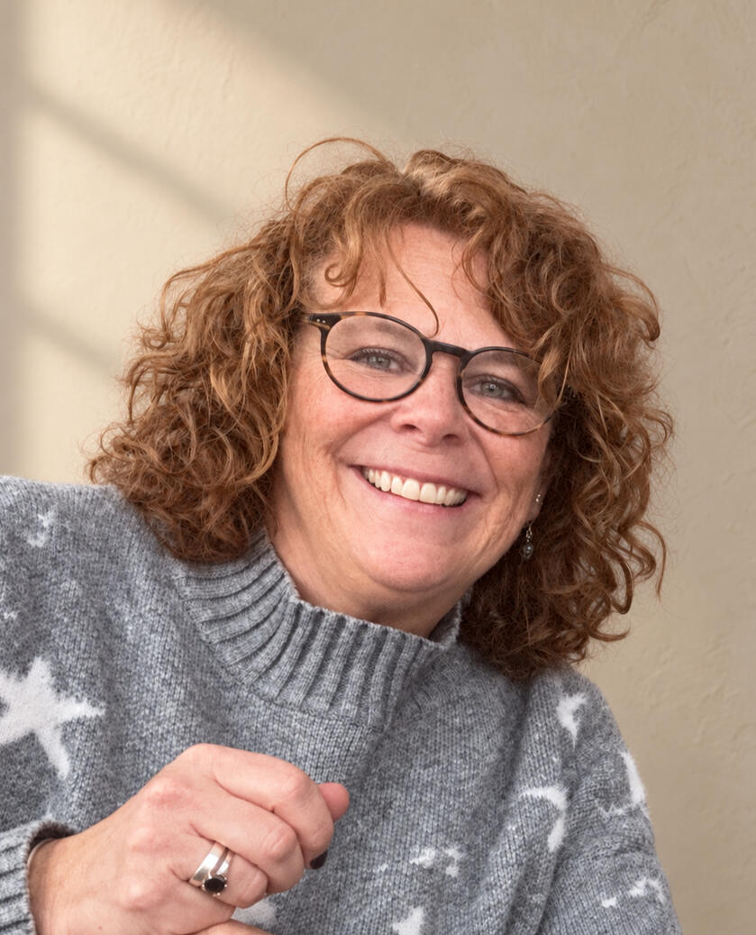 Leann Boggs, owner of Gear Theory, smiling against a warm, softly textured background.